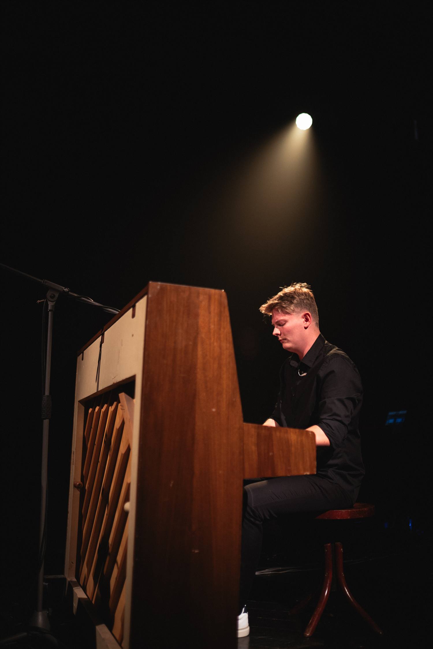 Marián Púčik hrá na pianíne v kuželi teplého reflektora