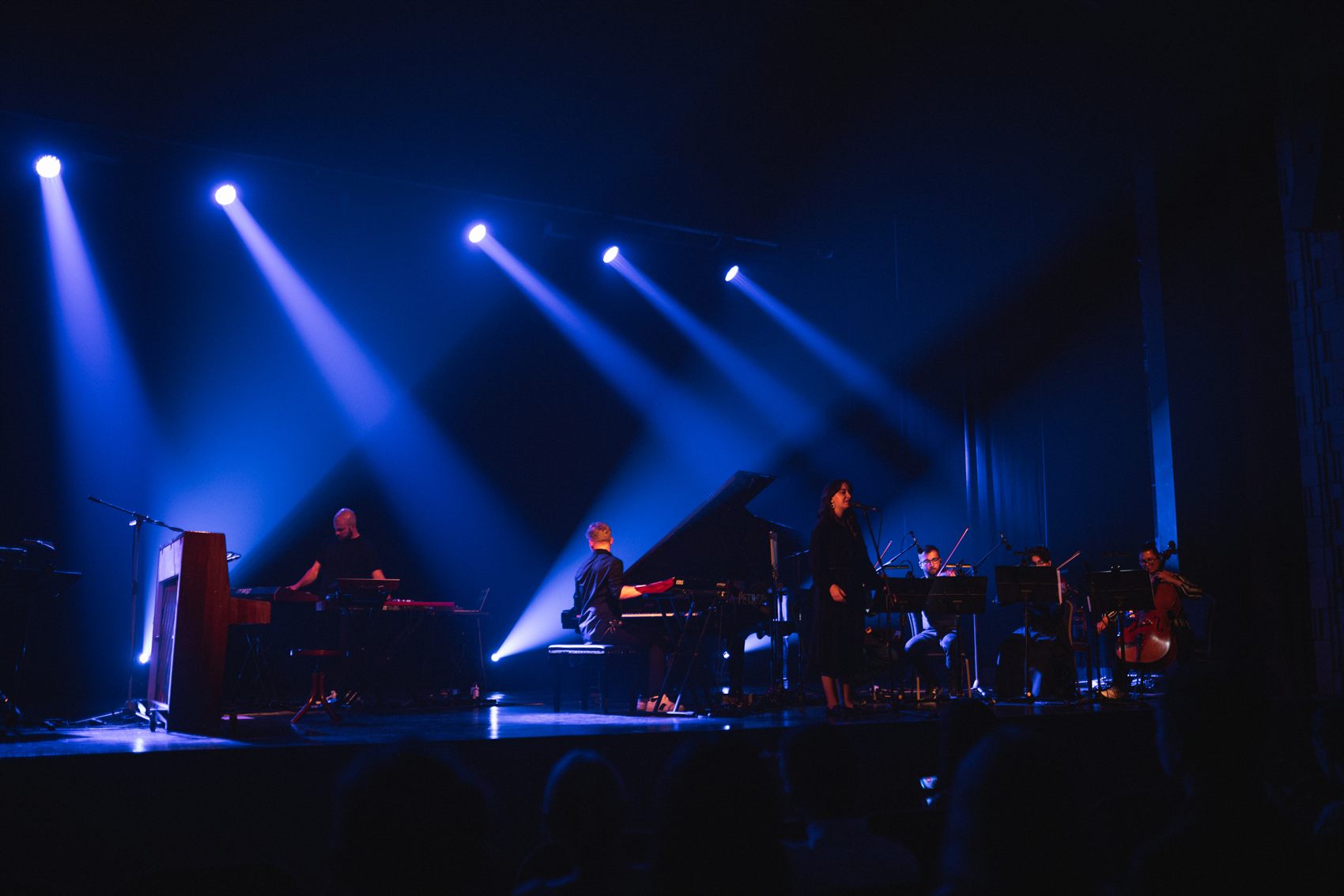 Koncert Od chaosu k pokoju: klavír, speváčka, sláčiky a klávesy na javisku v modrom svetle